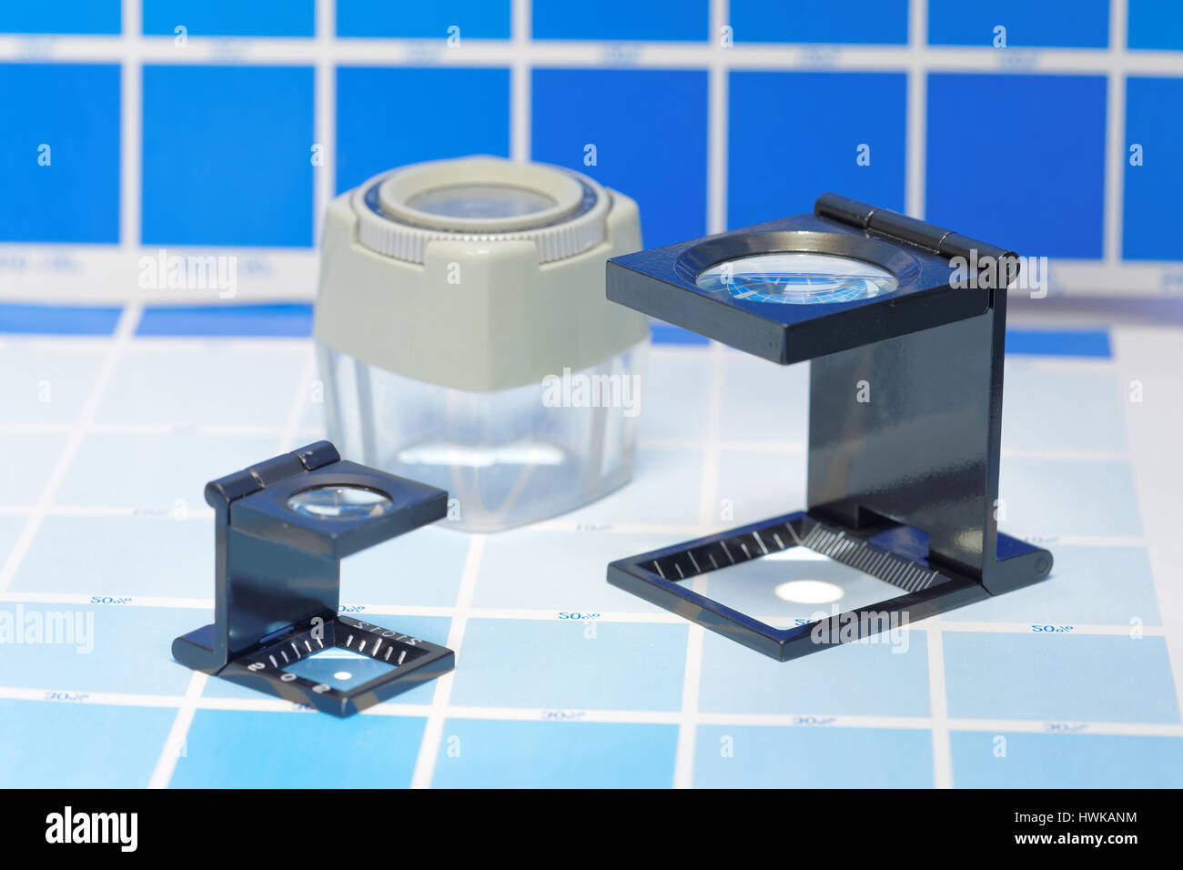 Three magnifier or printer's loupe sits on a cyan test sheet in a pre ...