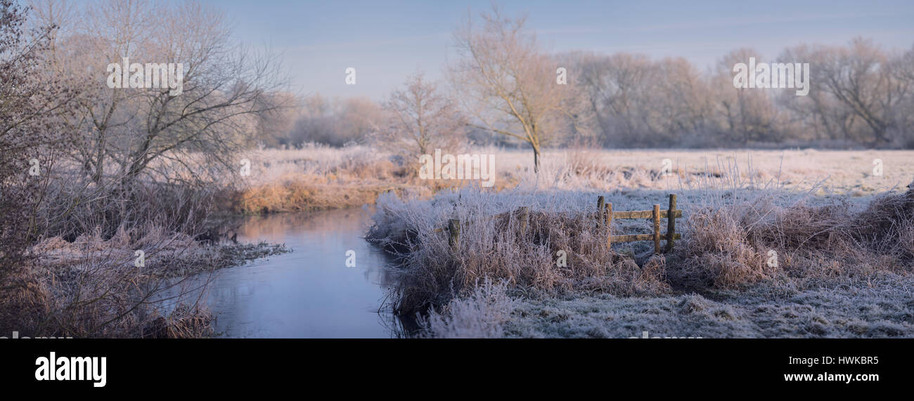 Landscape panorama of a stile and peaceful river on frosty morning in the icy English countryside on a winter morning at dawn. Very high resolution Stock Photo