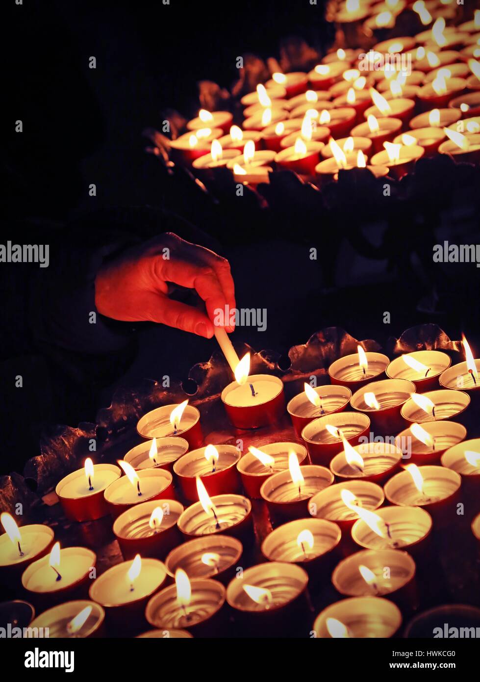 hand of an elderly woman hand lighting a candle during the Holy Mass in ...