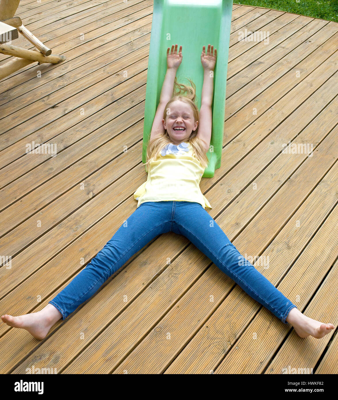 Carefree girl laughing with glee after sliding down the slide on her deck. Polish child age 8 having fun. Zawady Central Poland Europe Stock Photo