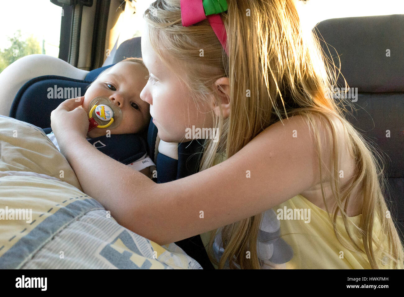 Sister attending to her baby brother in the car. Polish girl  watching baby in auto age 8 and 7 months. Zawady Central Poland Europe Stock Photo