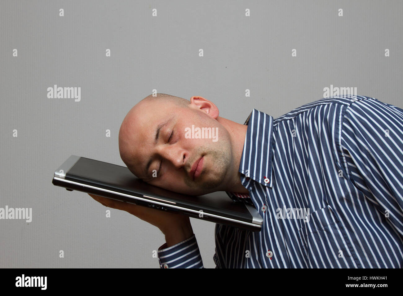 Businessman tiring and sleeping on his laptop in outdoor scene - overworked concept Stock Photo