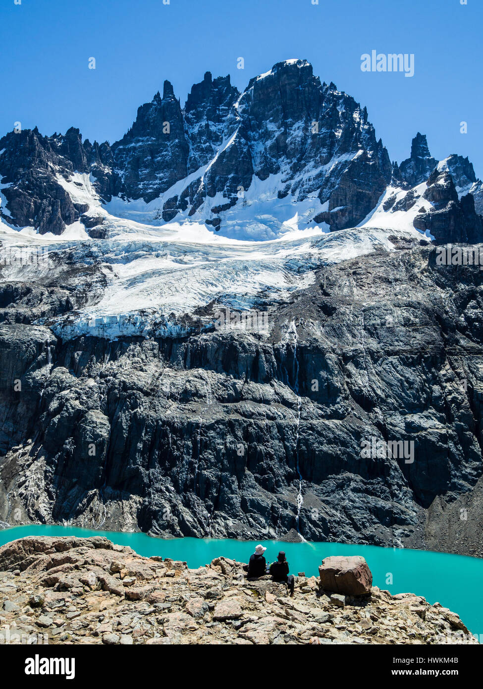 Couple sitting above  the lagoon below mountain Cerro Castillo, view towards glacier and peak Cerro Castillo, nature reserve Cerro Castillo, Reserva N Stock Photo