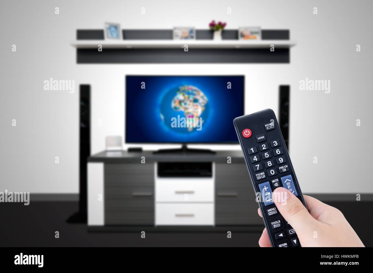 Watching television in modern TV room. Hand holding remote control Stock Photo