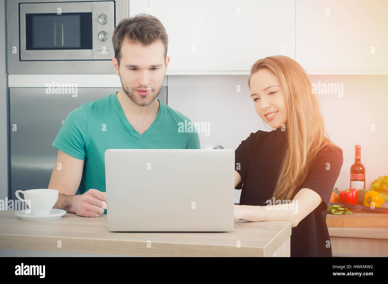 Couple uses the computer in the kitchen. lifestyle couple kitchen cooking home happy breakfast young concept Stock Photo
