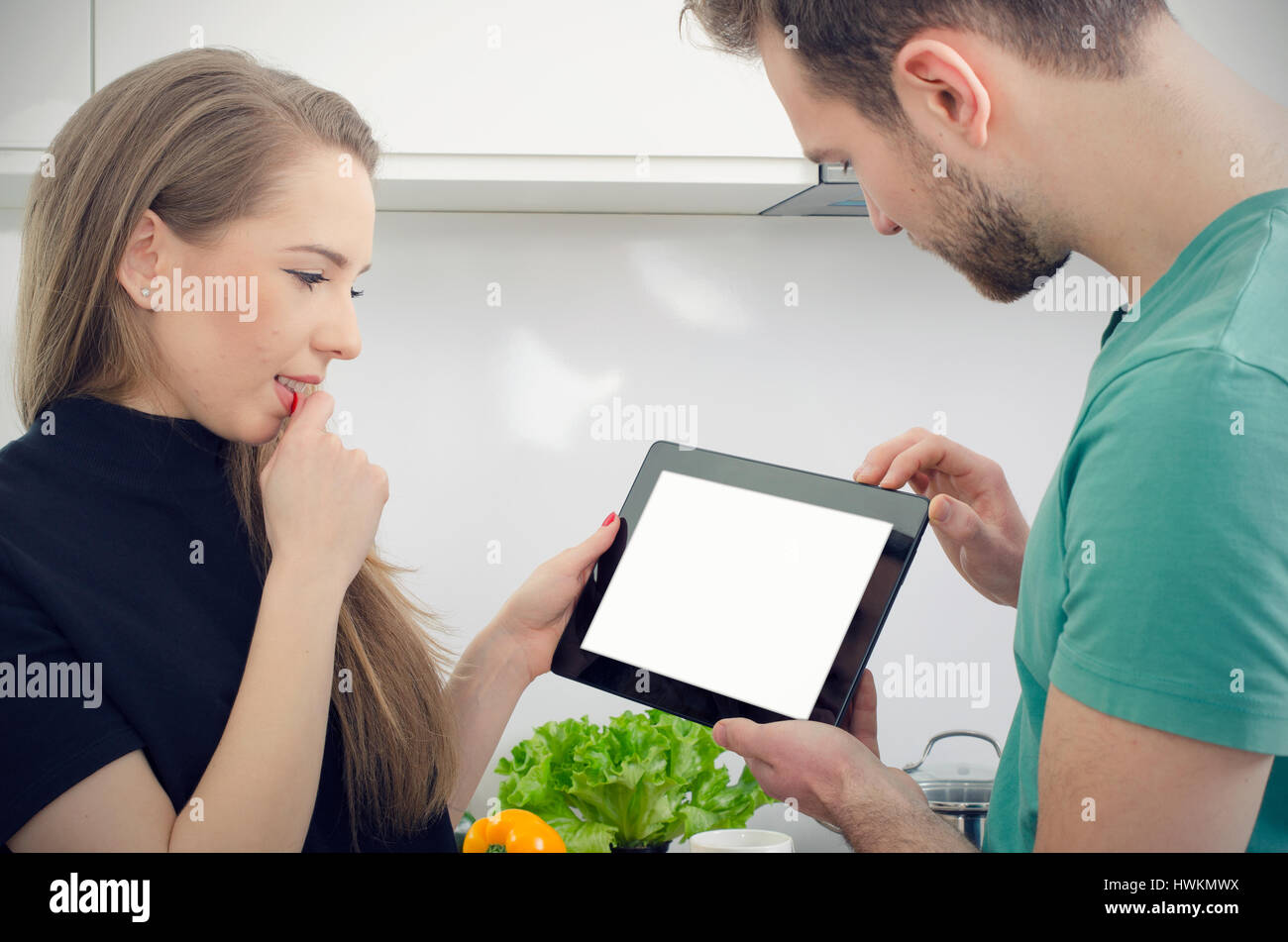 Young people cooking in the kitchen, check top recipes on tablet. kitchen couple home cooking male female tablet concept Stock Photo