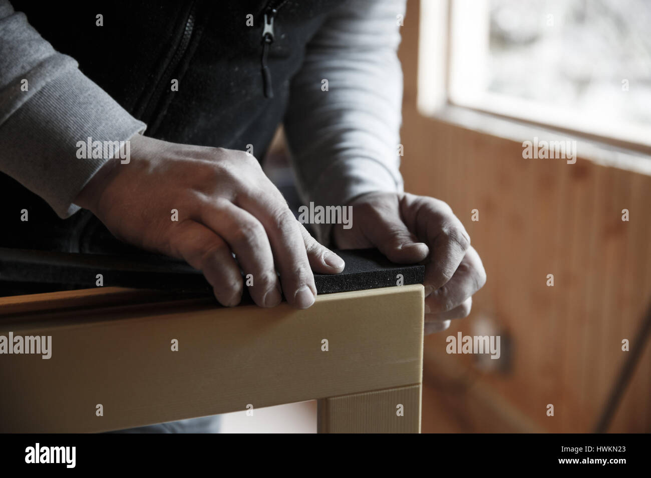 Worker preparing to install new three pane wooden windows in an old wooden house. Home renovation, sustainable living, energy efficiency concept. Stock Photo