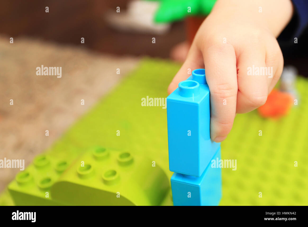 Child play with colorful constructor close-up. Kid build tower with cubics. Bright playing background. Stock Photo