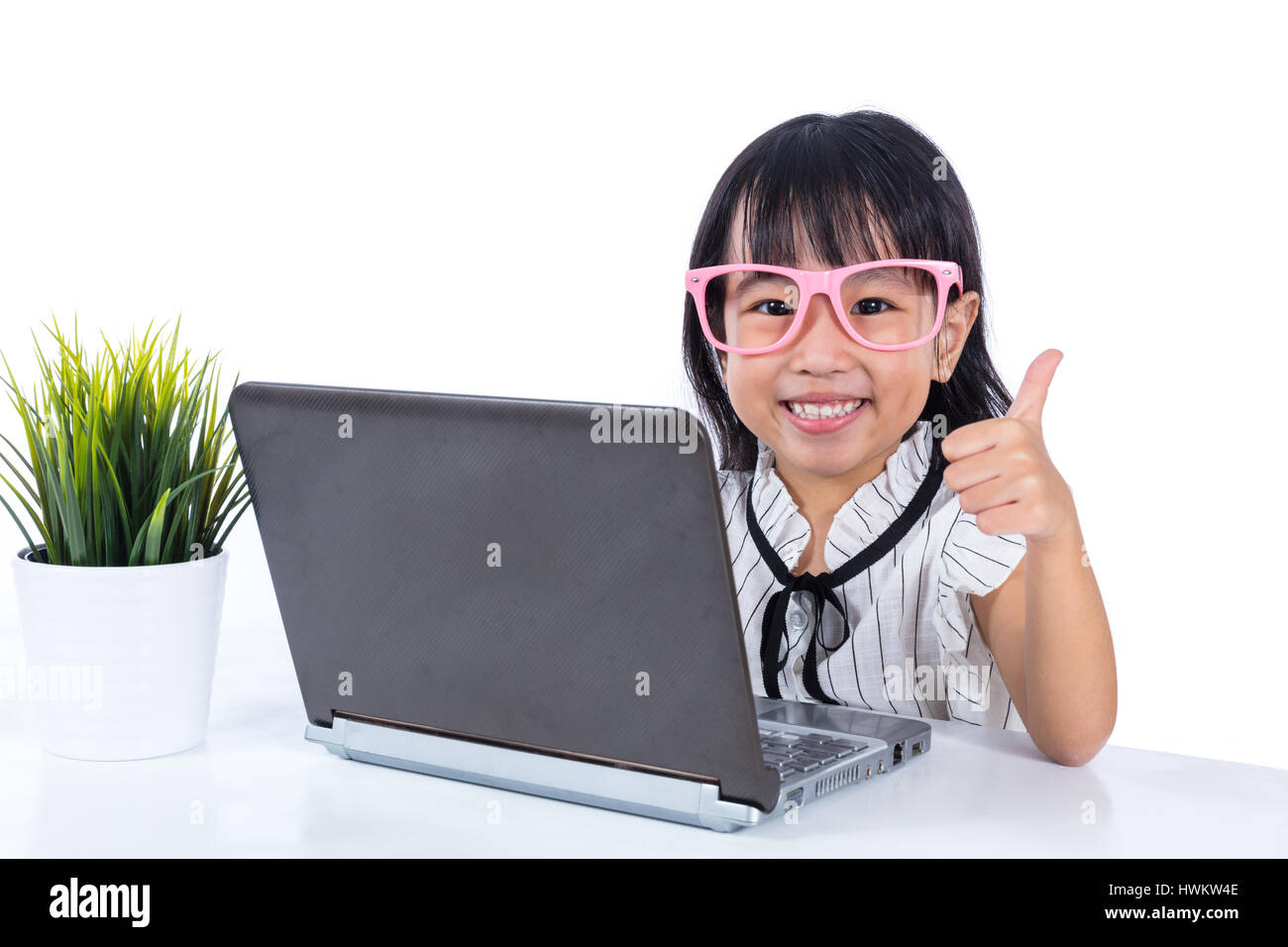 Smiling Asian Chinese little girl using laptop with thumbs up in ...