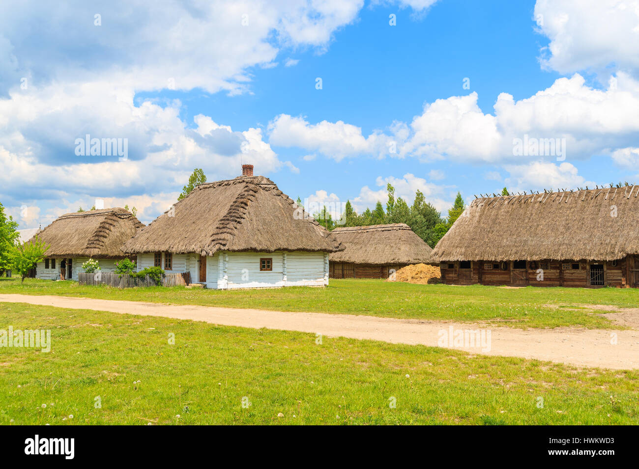 Rural road and old traditional houses with straw roof in Tokarnia village on sunny spring day, Poland Stock Photo