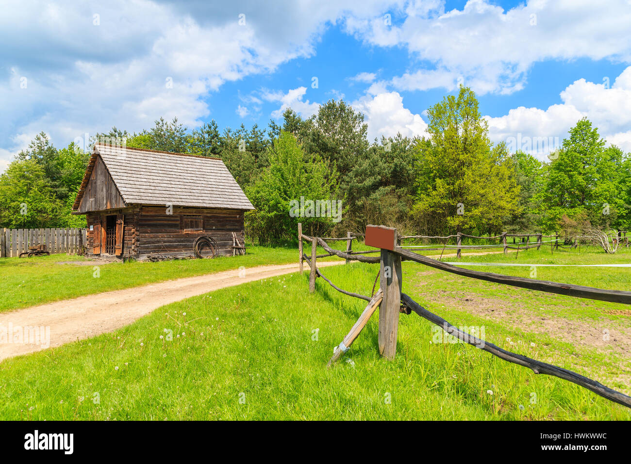 Rural road and wooden pasture fence in Tokarnia village on sunny spring day, Poland Stock Photo