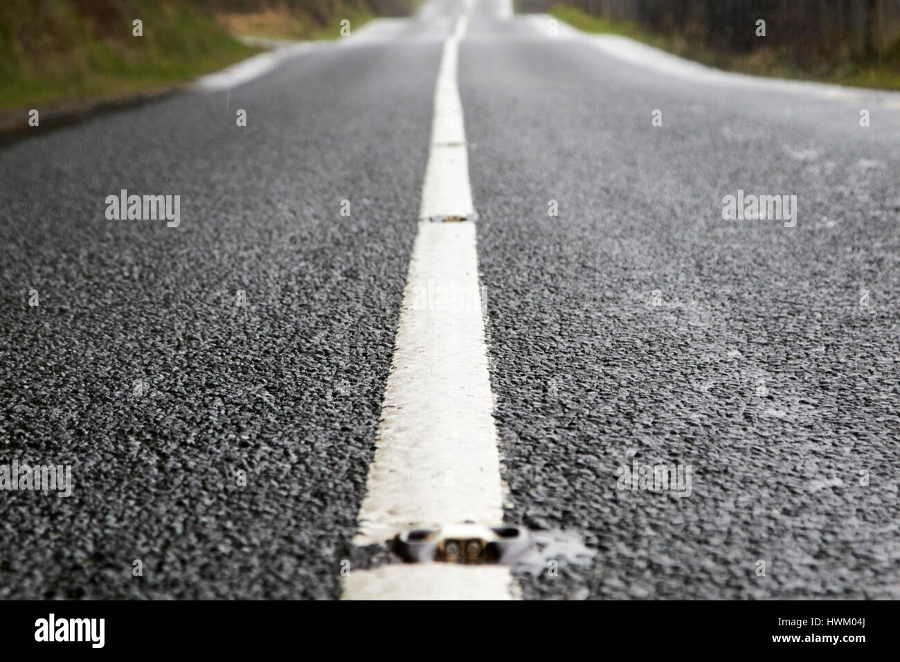 solid white paint in the centre of a wet irish rural road in county sligo Stock Photo
