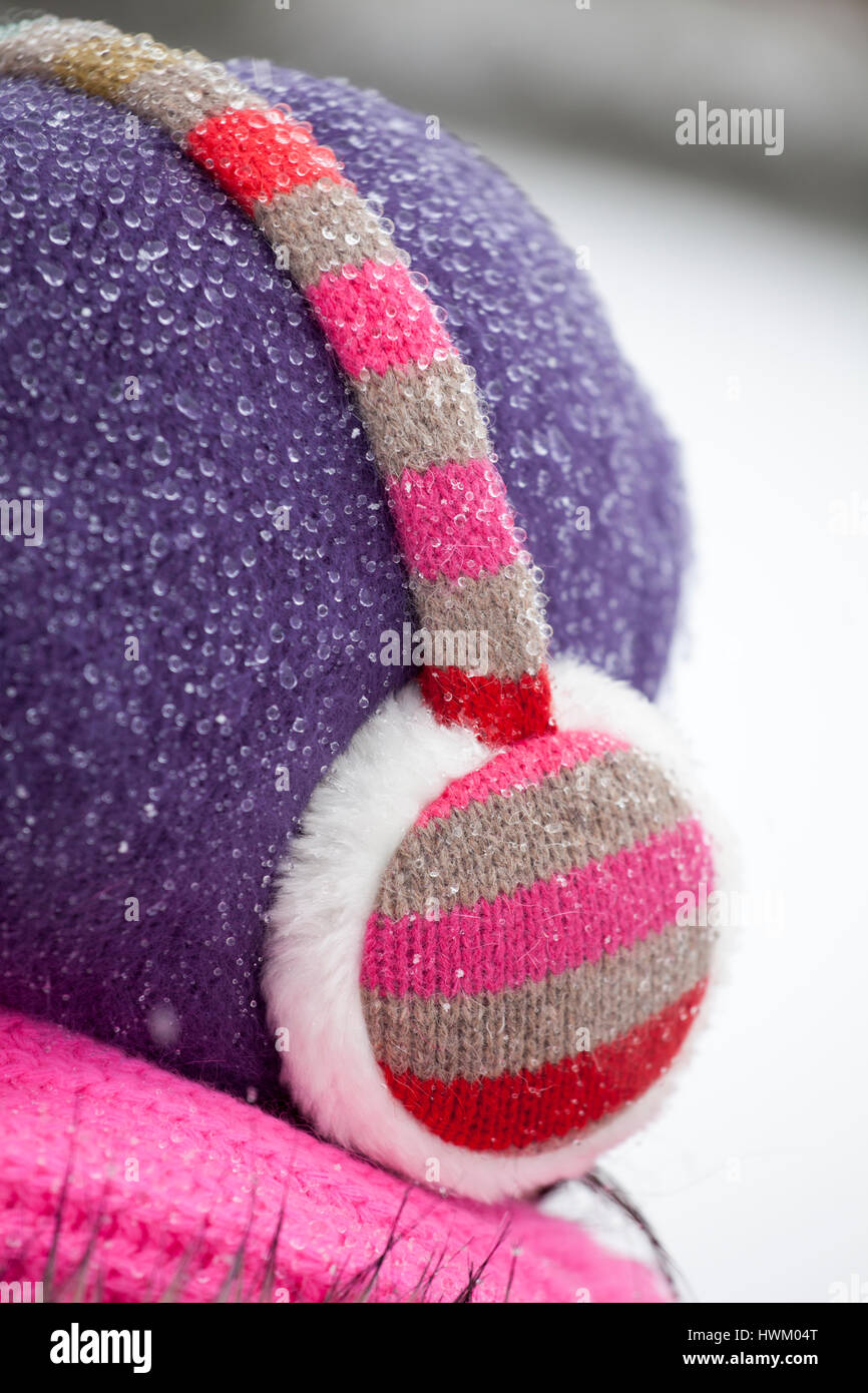 A woman wearing ear muffs and a woolly hat covered in raindrops Stock Photo