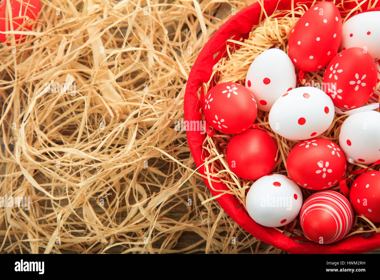 Colorful Easter eggs in a basket on straw background Stock Photo - Alamy