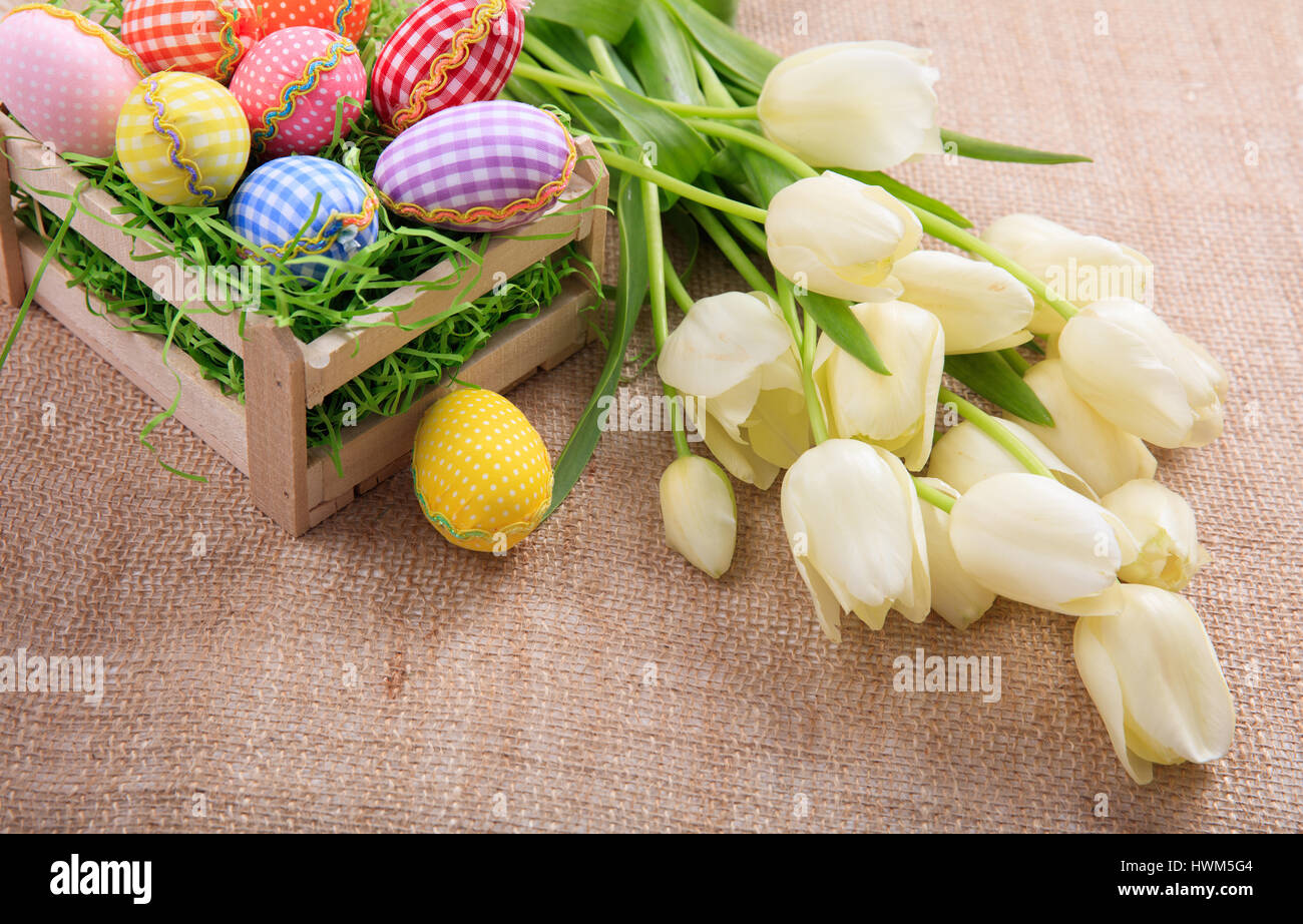 Colorful Easter eggs and white tulips on a burlap Stock Photo - Alamy