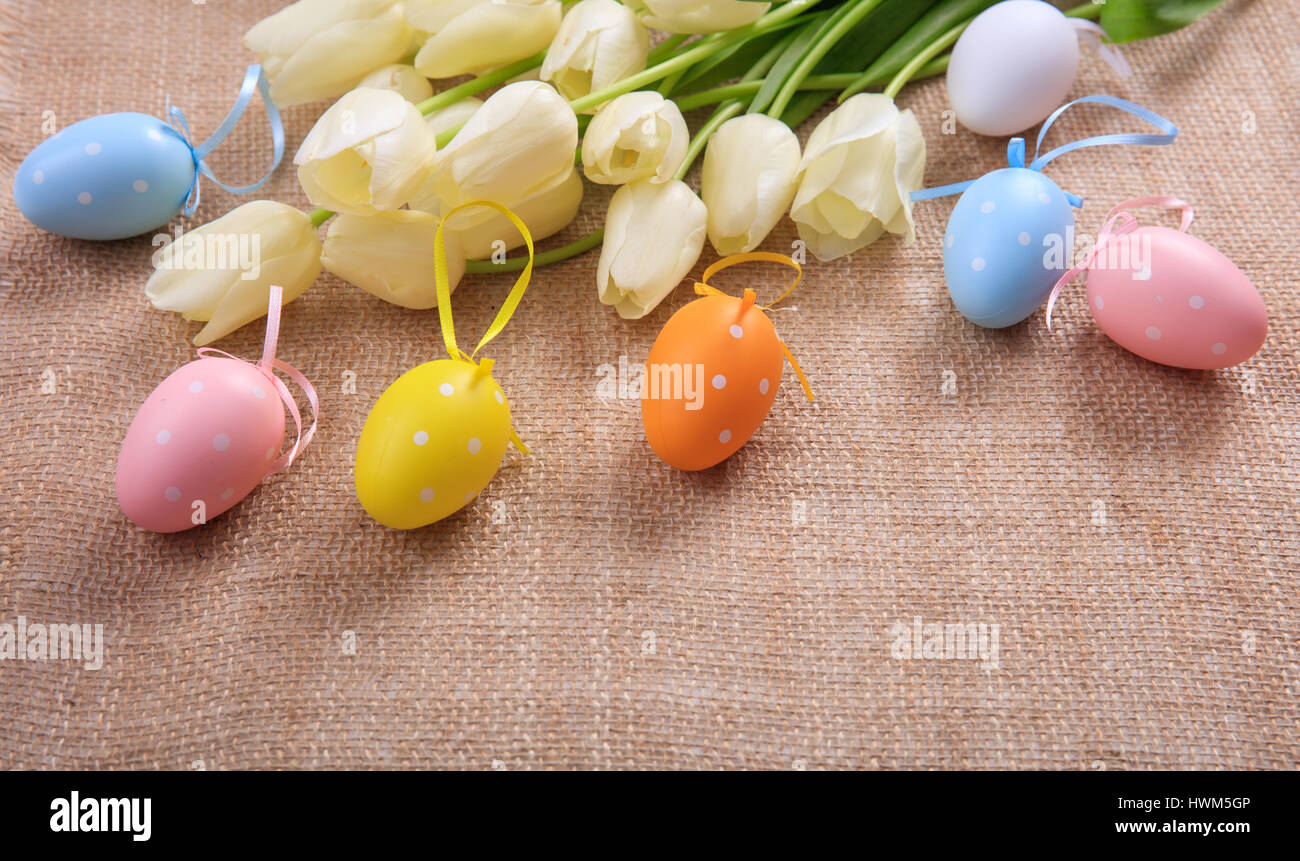 Colorful Easter eggs and white tulips on a burlap Stock Photo - Alamy
