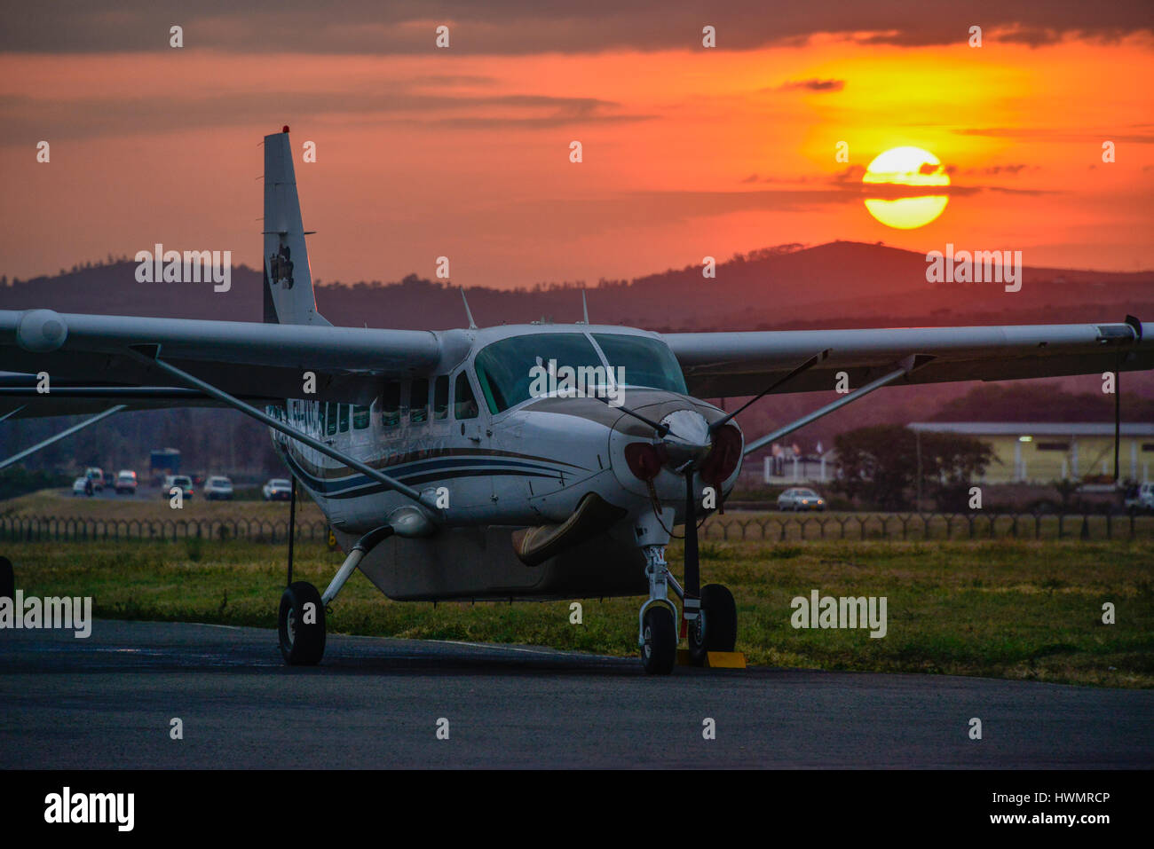 The sun sets behind a Cessna 208 Caravan aircraft at Arusha airport in Tanzania, Africa. Stock Photo