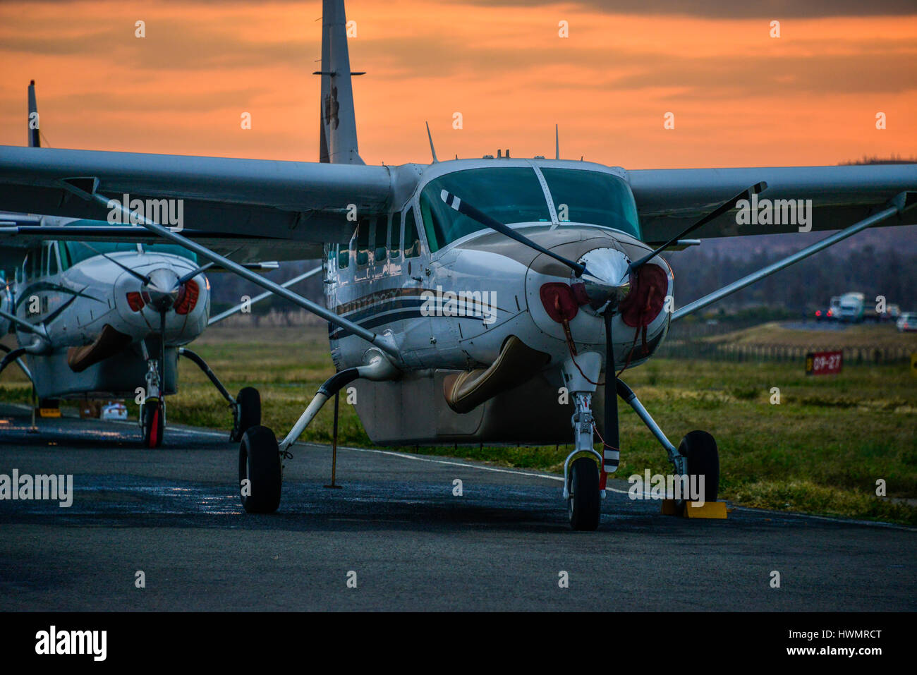 The sun sets behind two Cessna 208 Caravan aircraft at Arusha airport in Tanzania, Africa. Stock Photo