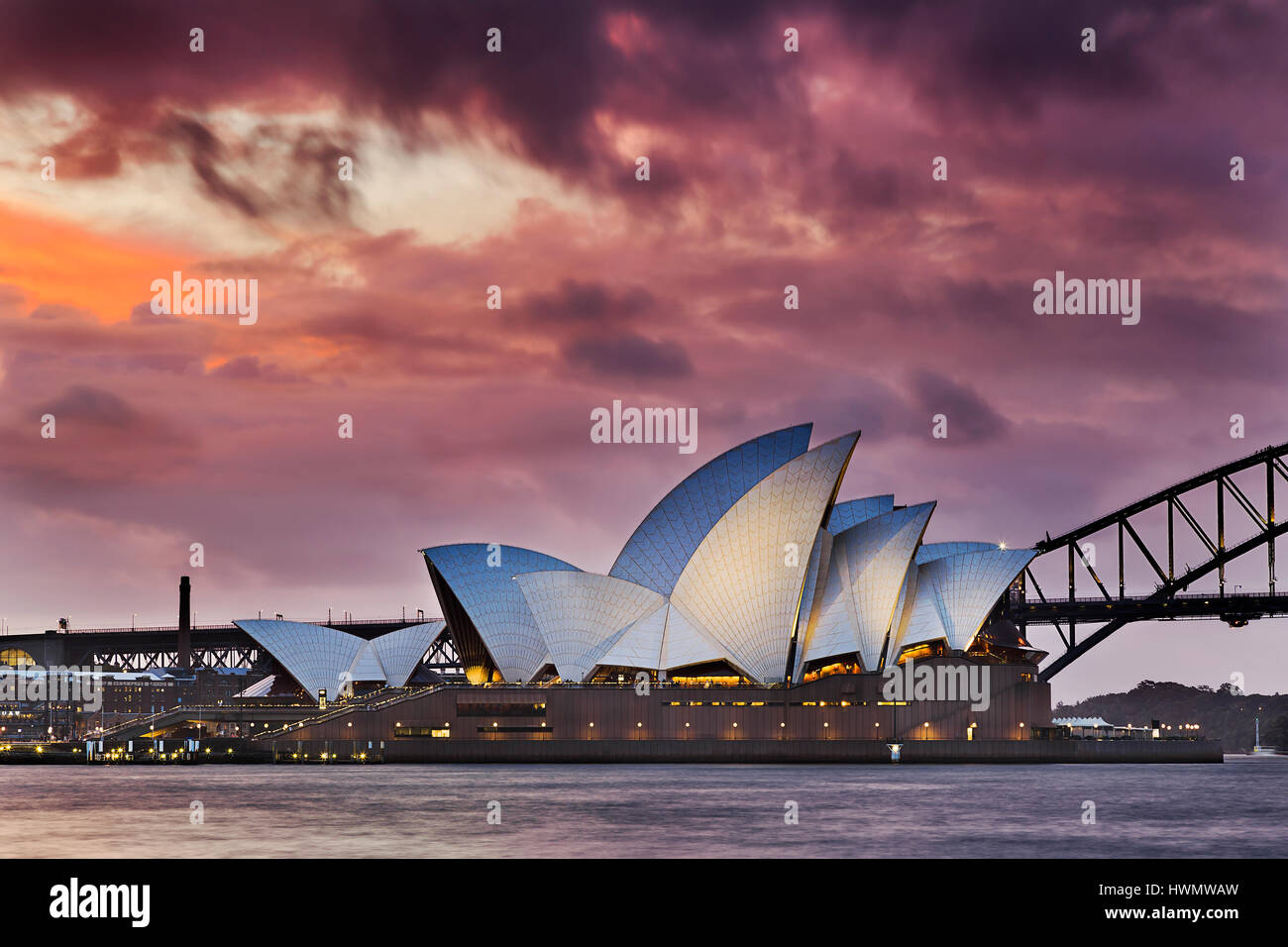 Sydney, Australia - 19 March 2017: Colourful sunset through thick clouds over world famous landmark - Sydney Opera house and Harbour Bridge. Stock Photo