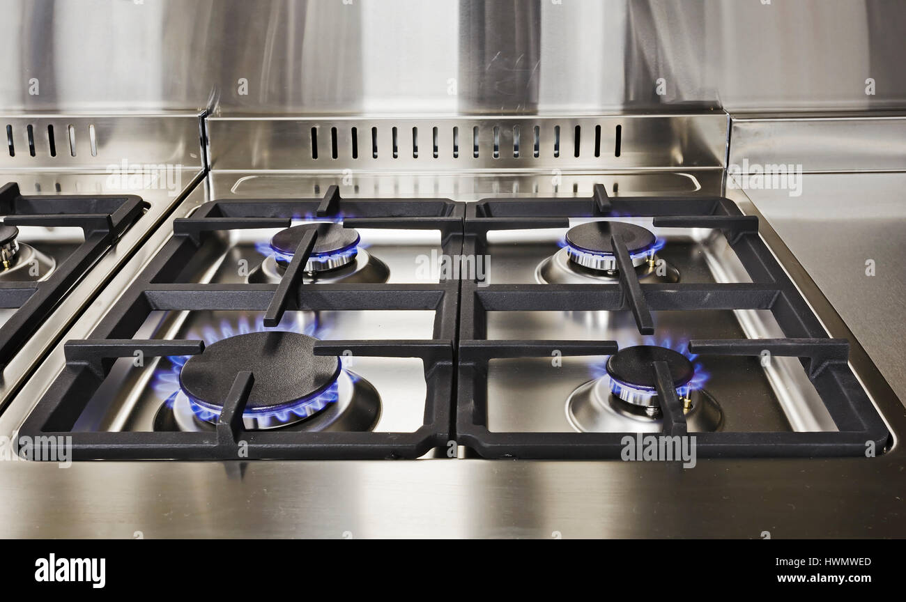 Burning blue flames of gas on cooktop under grills in a modern clean