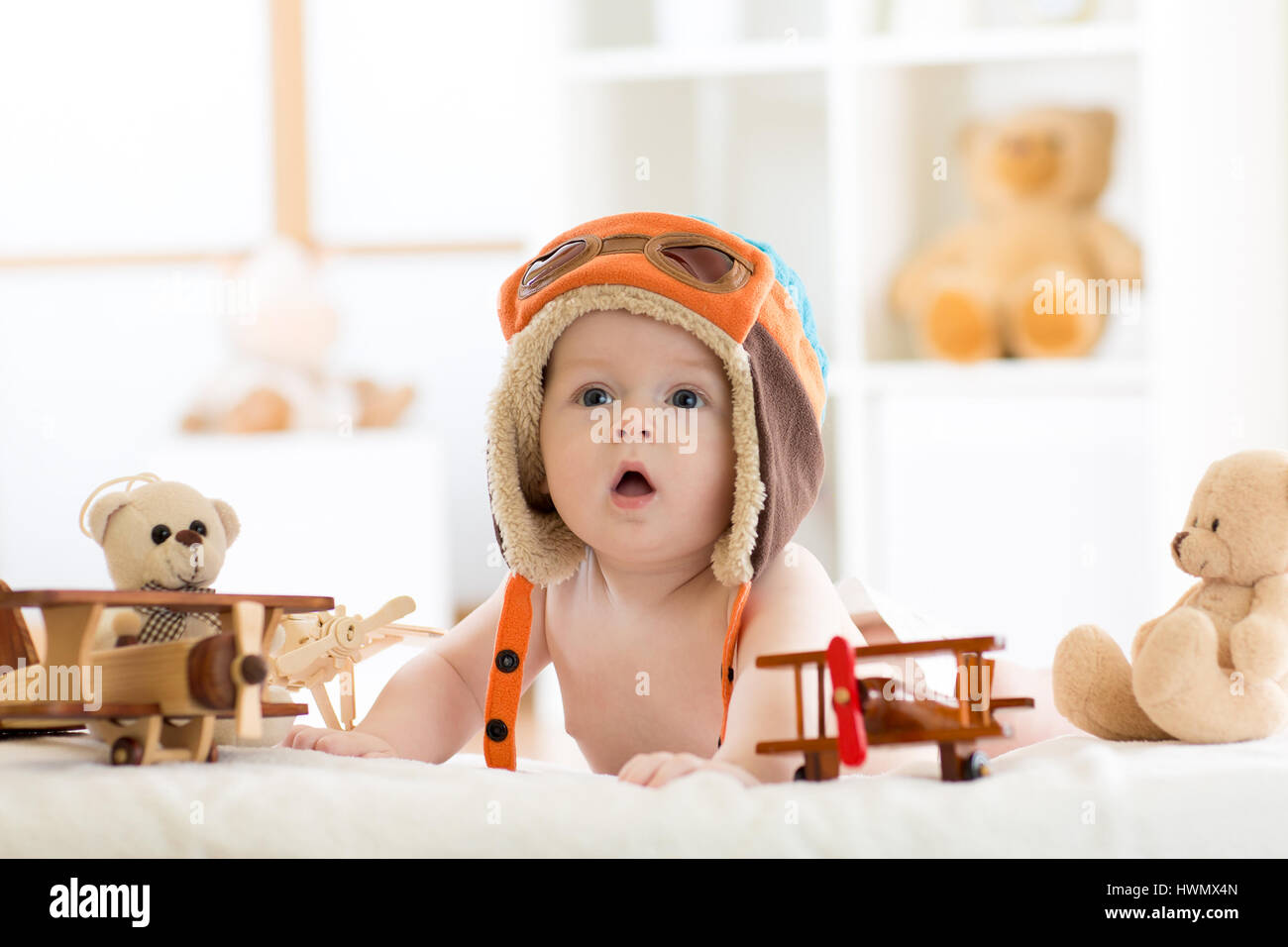 Funny baby boy weared pilot hat with wooden airplane and teddy bear toys Stock Photo