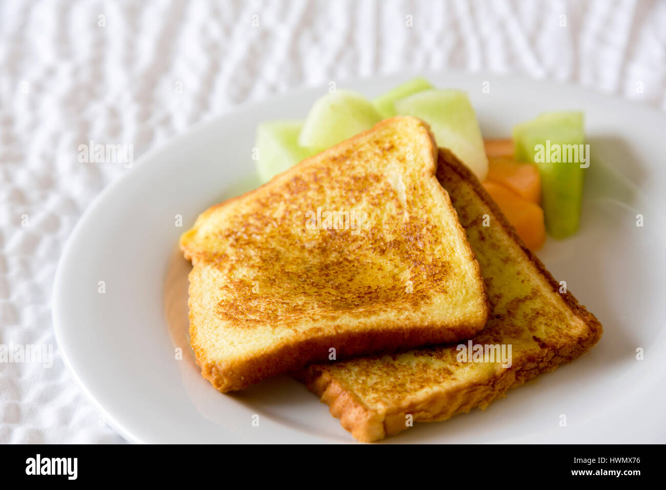 Two slices of French Toast placed with melon in horizontal photograph