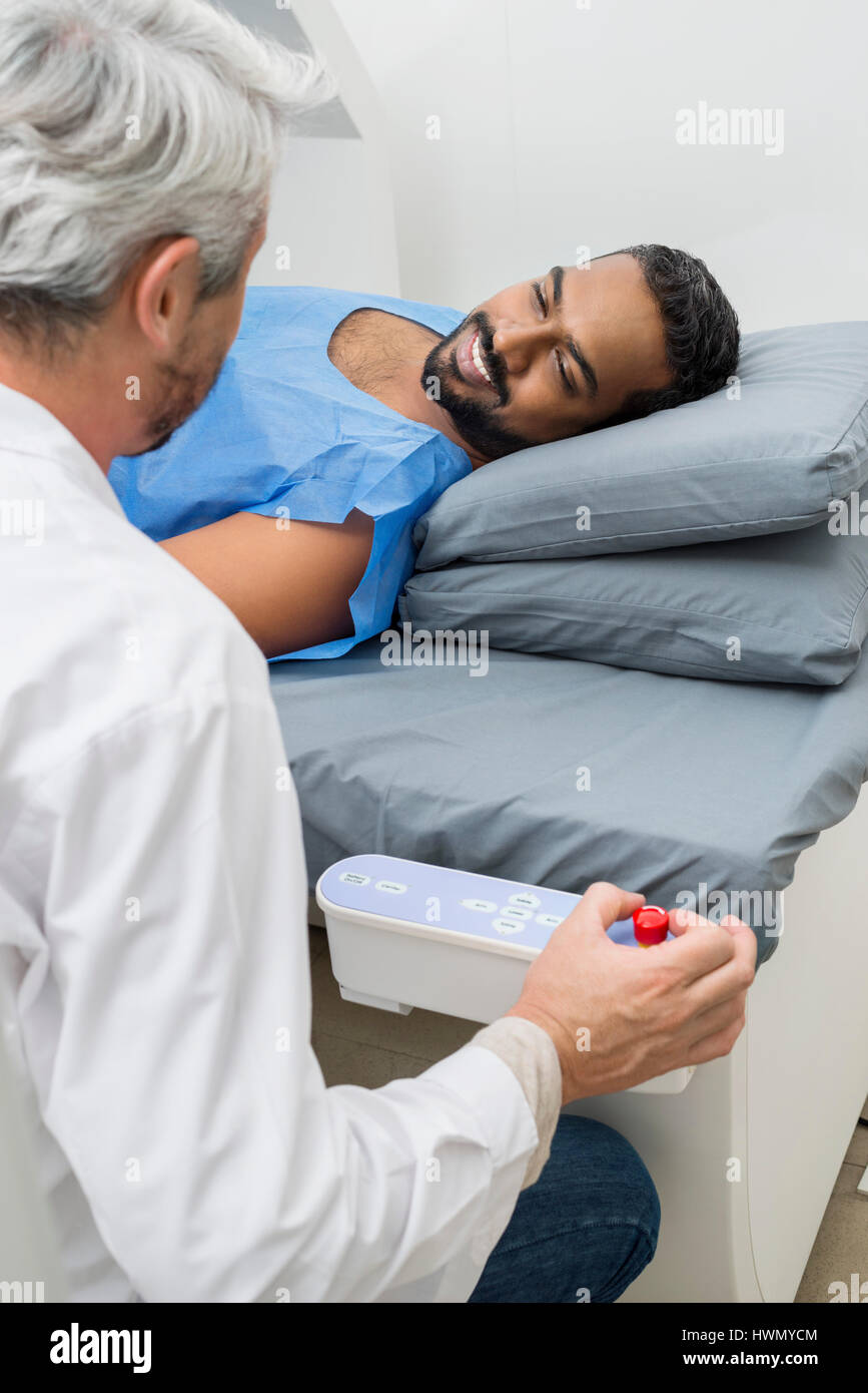 Man Lying On Bed While Looking At Doctor In Hospital Stock Photo