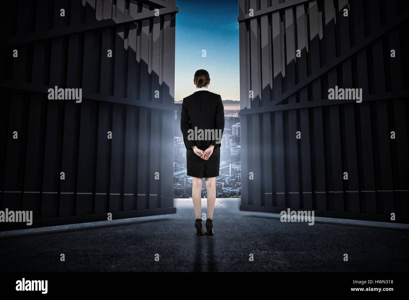 Young businesswoman standing with hands behind back against beautiful view of city skyline 3d Stock Photo