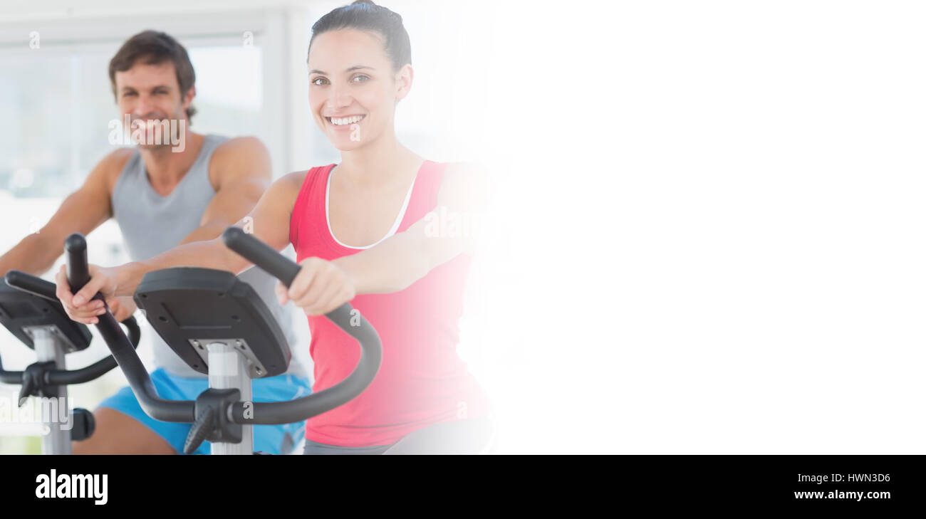 Smiling young couple working out at spinning class in a bright gym ...