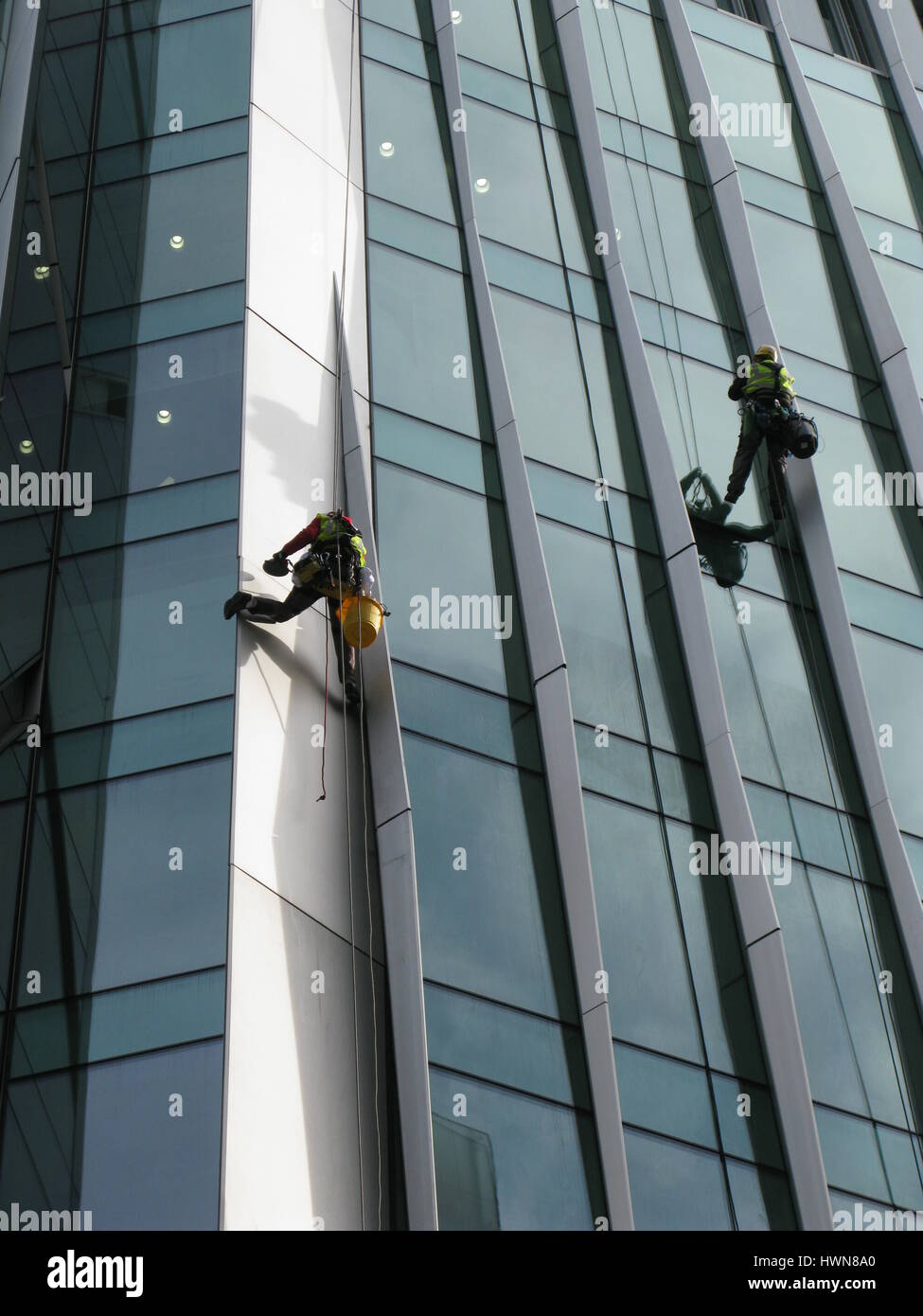 London, United Kingdom - March 14, 2016: Construction abseilers fix curtain wall of building Stock Photo