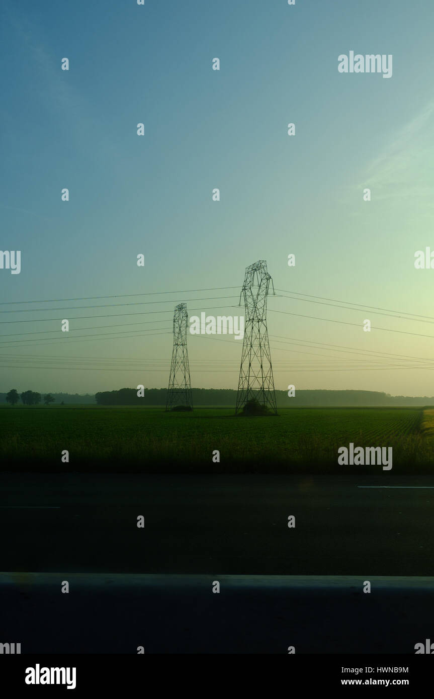 View of High Tension Power lines during sunset on the highway, Centre-Val de Loire, France Stock Photo