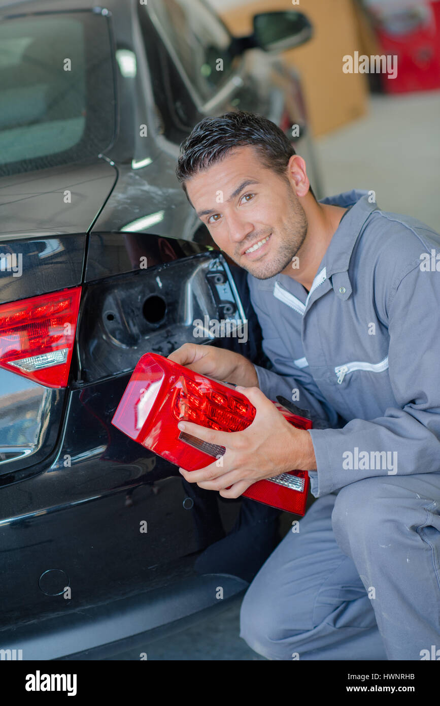 Mechanic fitting rear indicator unit to car Stock Photo Alamy