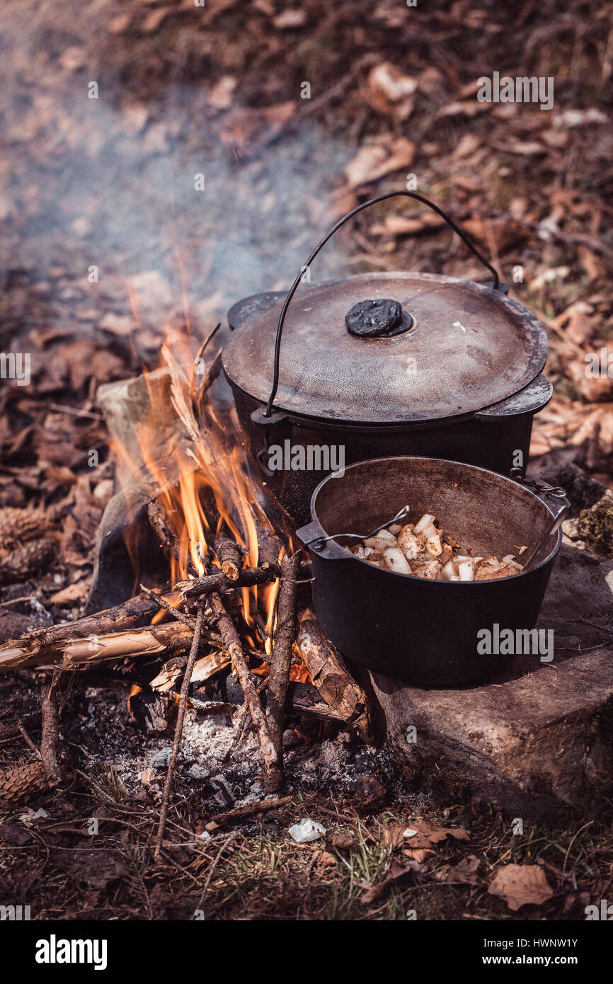 Cooking in the sooty cauldron on the open fire in woods. Stock Photo