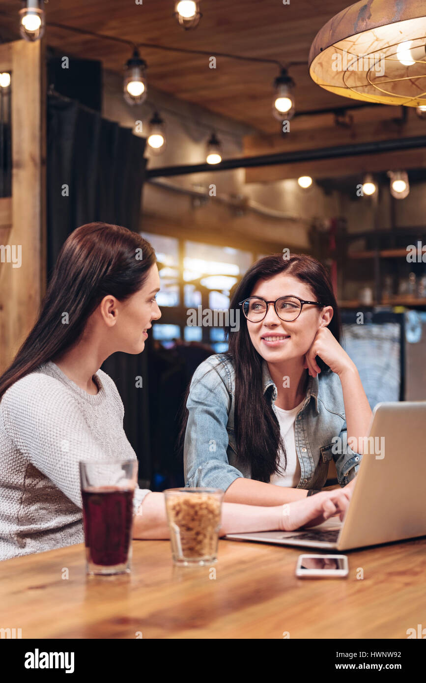 Best friends. Delighted girl wearing glasses sitting near her sister while  keeping her left hand near face Stock Photo - Alamy