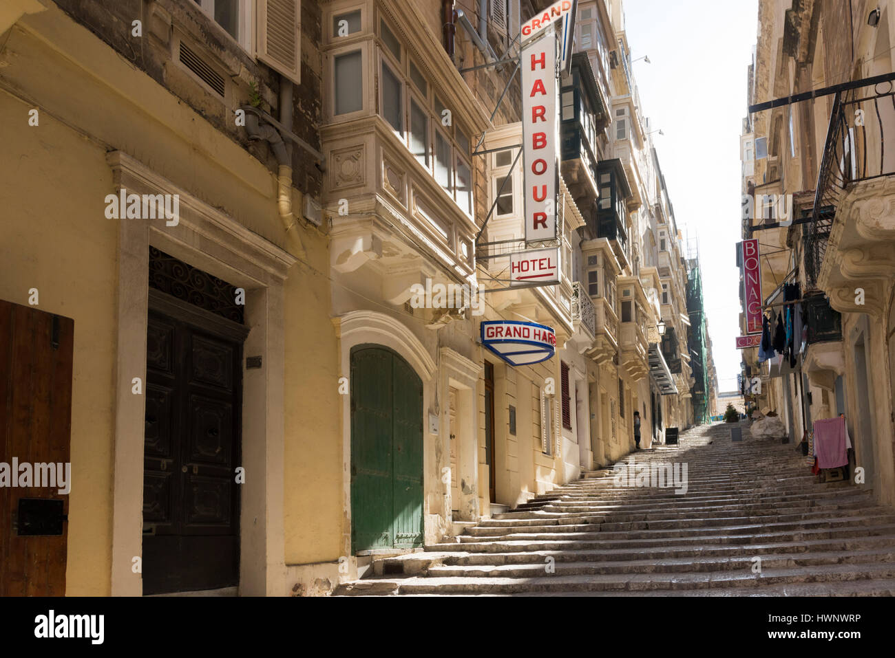A narrow street with stone steps near the Grand Harbour Hotel Valetta Malta with the sun streaming between the buildings. Stock Photo