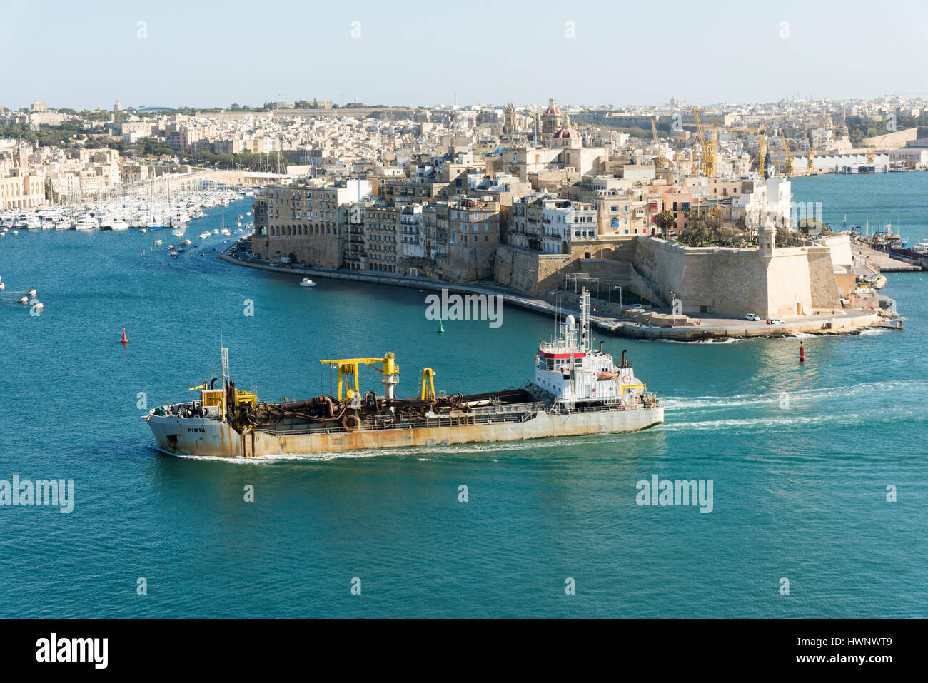 A view into the Grand Harbour from Valetta to the Three Cities with old buildings and a tanker ship at Vittoriosa Malta Stock Photo