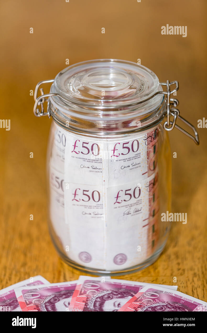 A large savings jar full of unused £50 notes London England UK Stock Photo