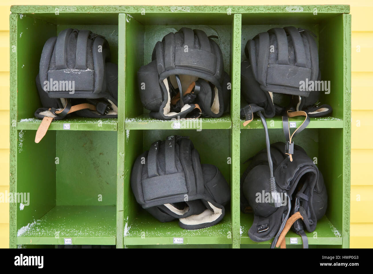 Russian tank winter helmets placed in order in green wooden box on military training ground. Russian abreviation KT means tank commander, MB means dri Stock Photo