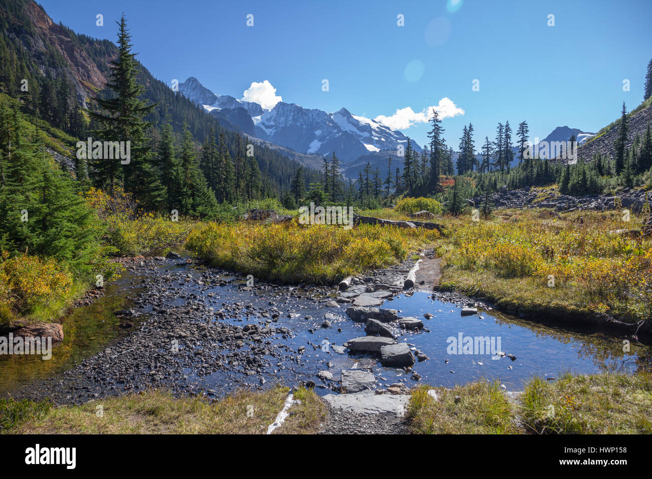 Shallow stream with stepping stones lies across the popular Lake Ann hiking trail near Mount Baker, WA Stock Photo
