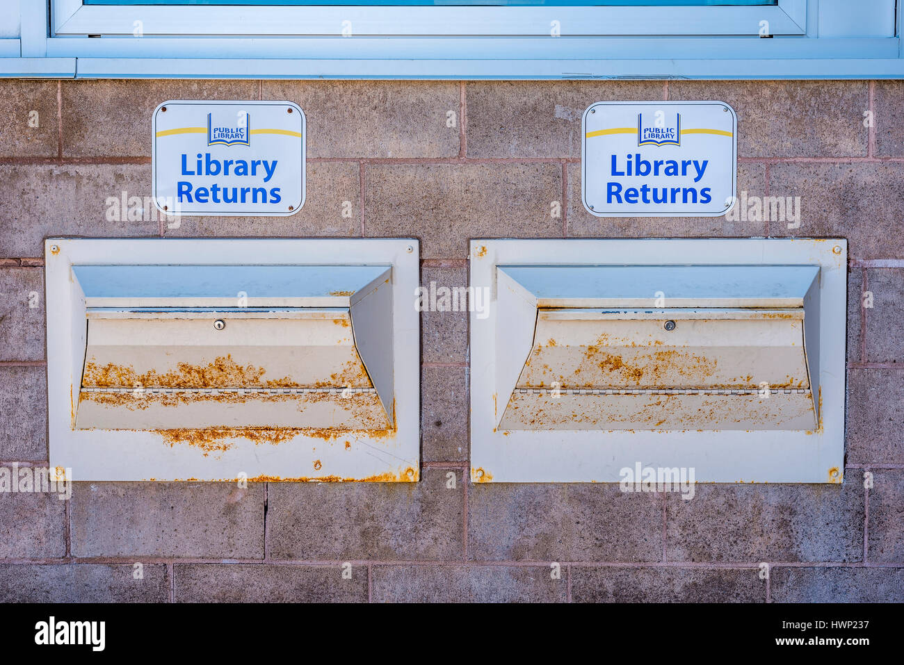 Two Public Library returns signs above the rusty chutes outside a the library in Stouffville Ontario Canada. Stock Photo