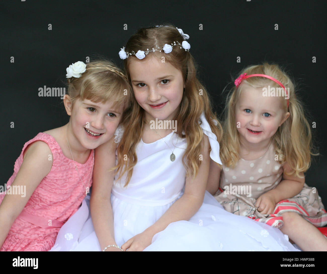 Portrait of sisters blonde girls, children kids hugging on first holy communion day Stock Photo