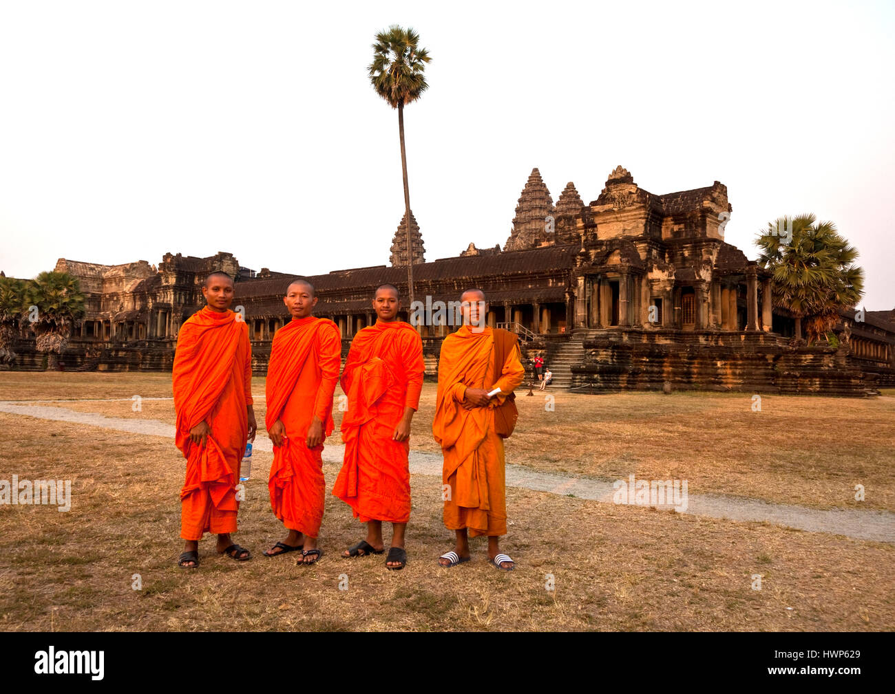 Four Buddhist monks in orange robes  pose in front of Angkor Wat Stock Photo