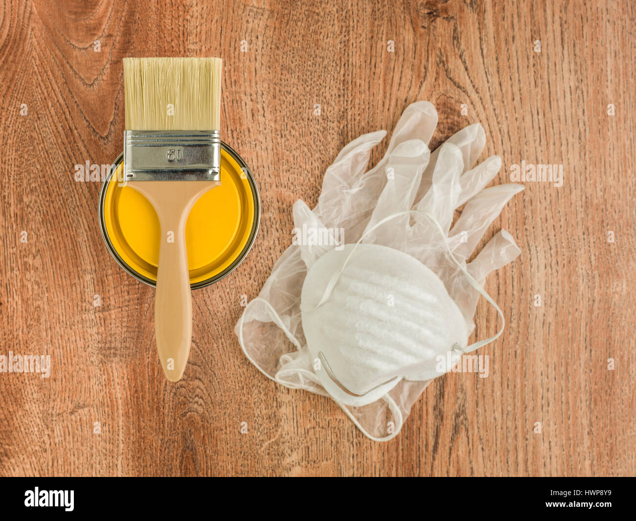 yellow paint can with brush and gloves on a wood background Stock Photo