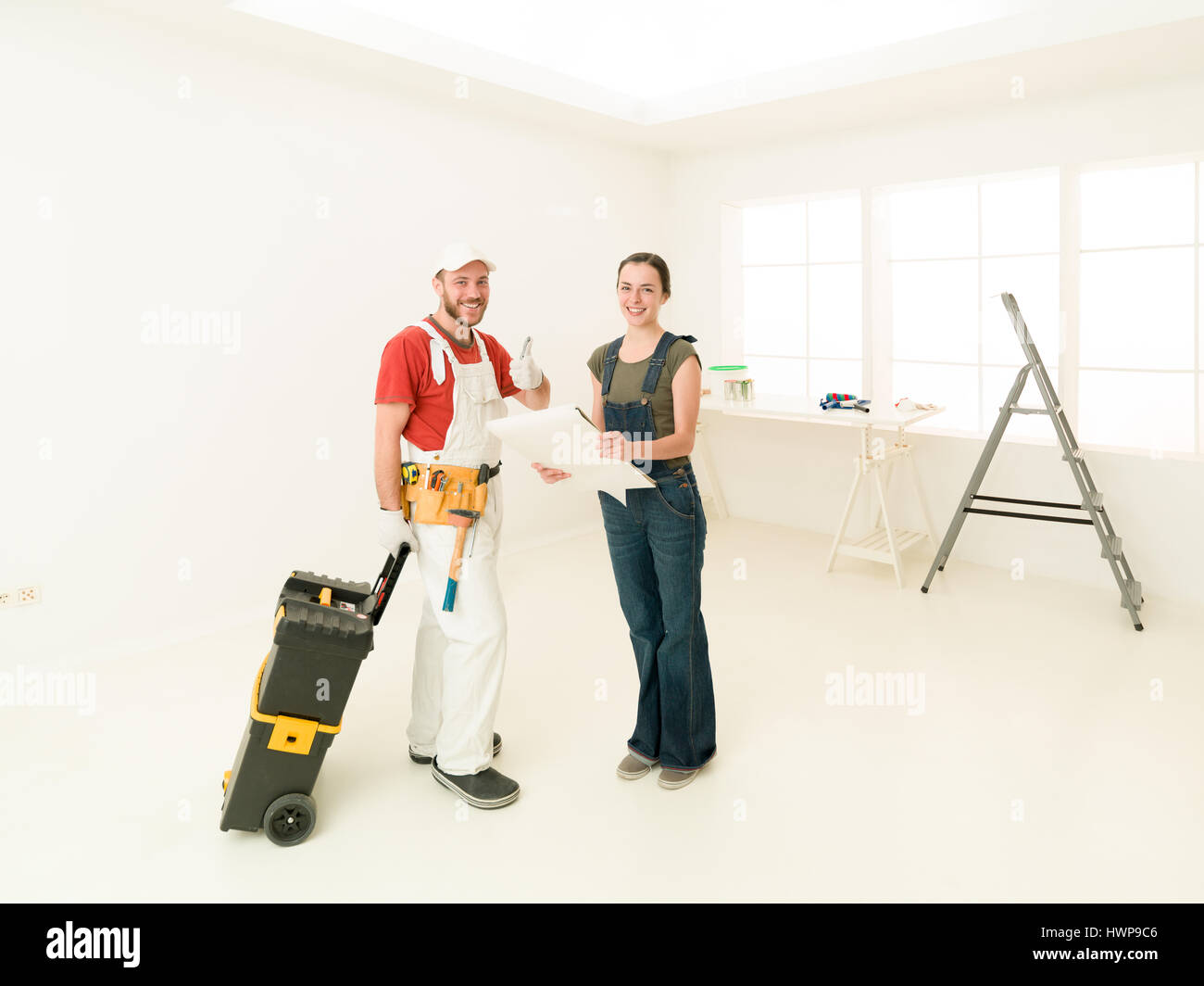 repair, building, renovation and people concept - contractor and client looking at blueprint at home, bright white interior Stock Photo