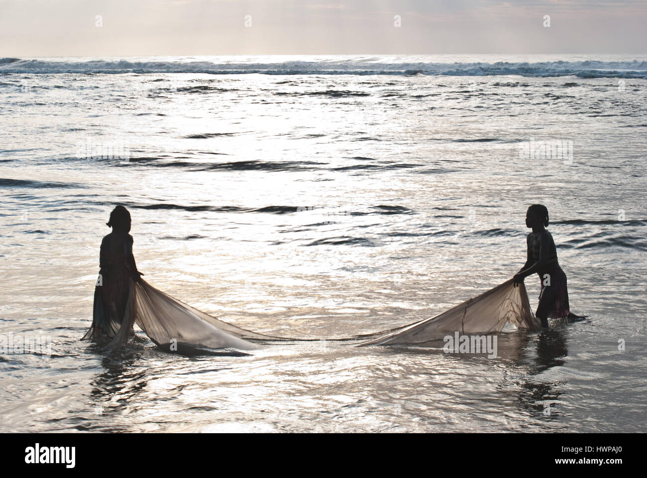 Two girls are fishing 'bichiques'( Madagascar). 'Bichiques' are fry of two species of freshwater fish belonging to the family of 'gobiidae'. Stock Photo