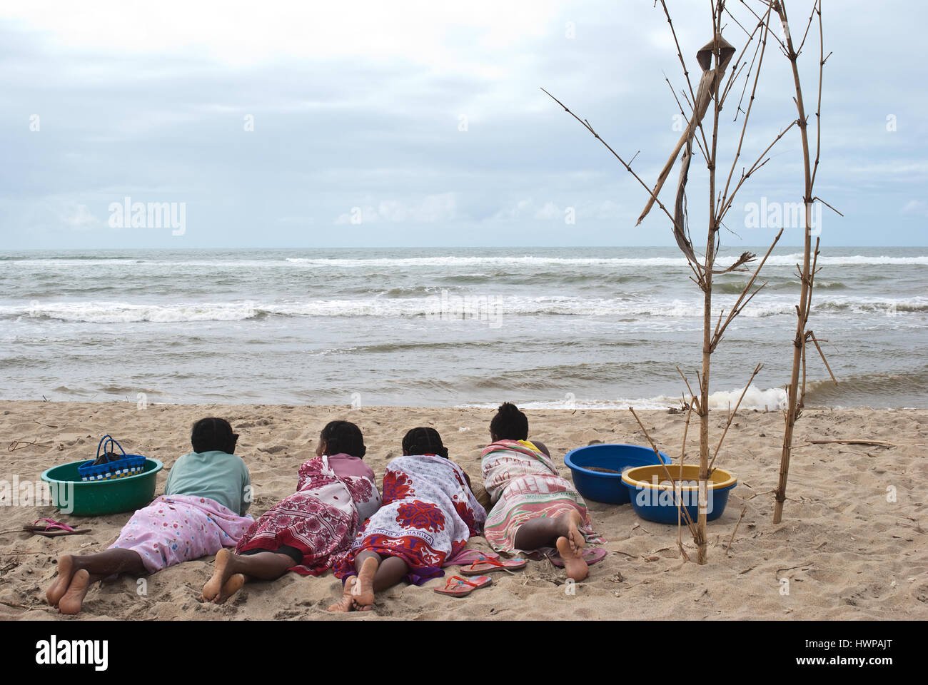 Four women are lying on a beach. They are waiting for the return of fishermen to collect fishes before going to the market to sell them ( Madagascar) Stock Photo