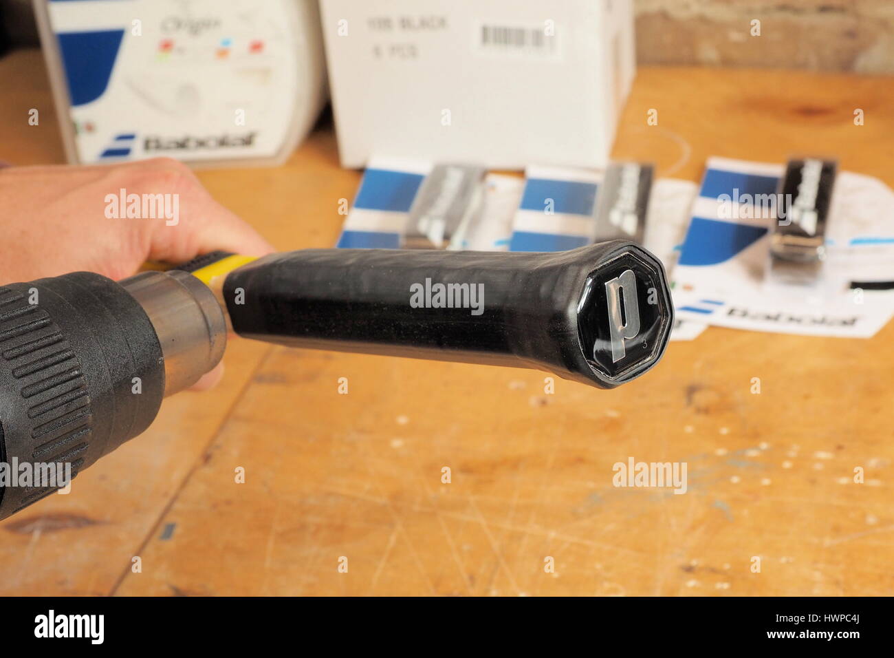 Melbourne, Australia, 2015, May 10: Tennis racquet handle in the process of upsizing by shrinking a heat shrink tube on to the handle base in a racque Stock Photo