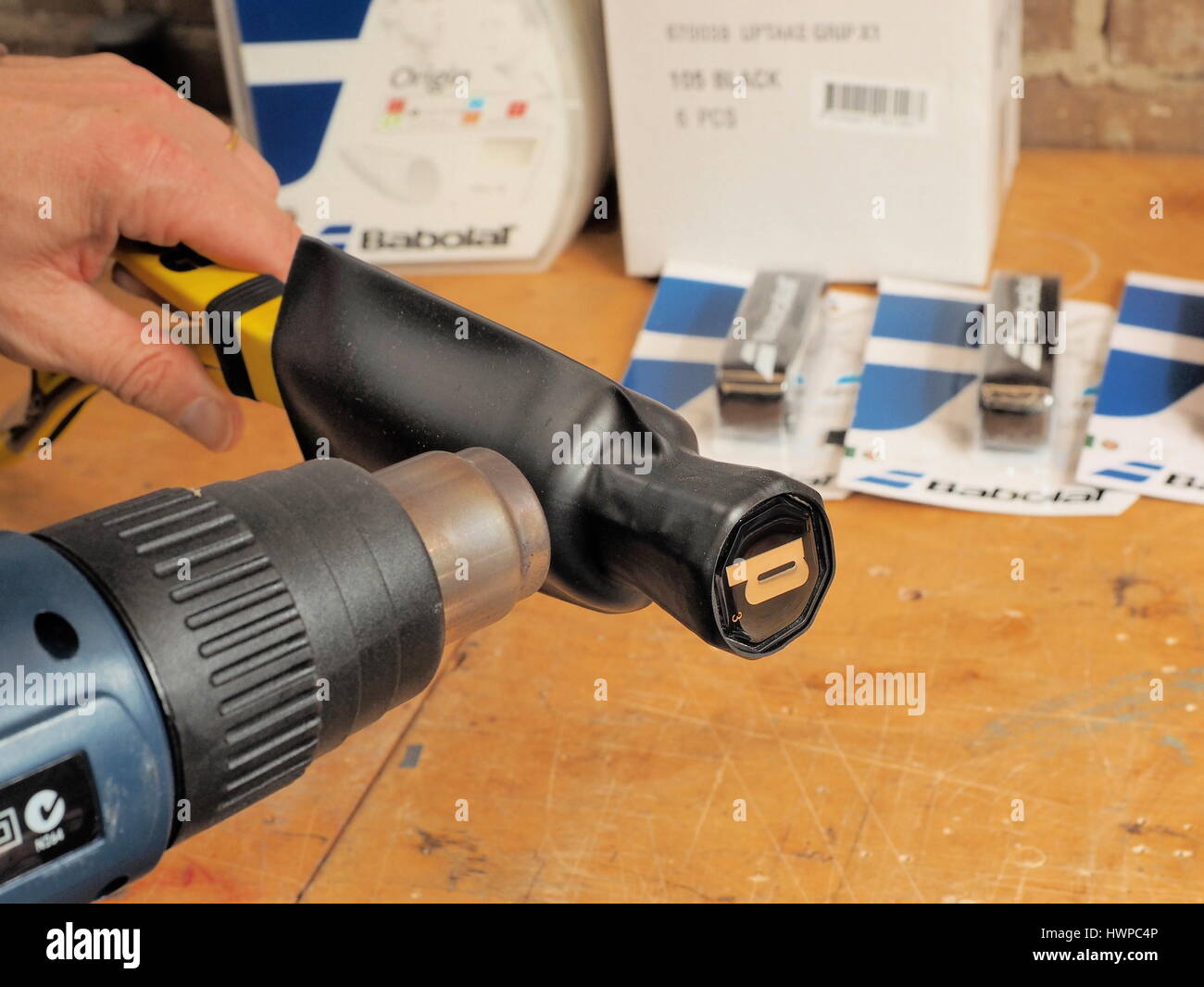 Melbourne, Australia, 2015, May 10: Tennis racquet handle in the process of upsizing by shrinking a heat shrink tube on to the handle base in a racque Stock Photo