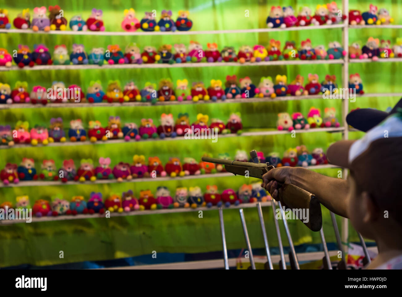 Carnival game shooting pop-caps at stuffed dolls for prize at festival in Thailand Stock Photo