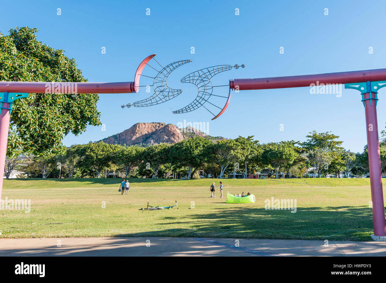 People relaxing and children playing at the Strand Park, Townsville, with iconic Castle Hill in the background Stock Photo